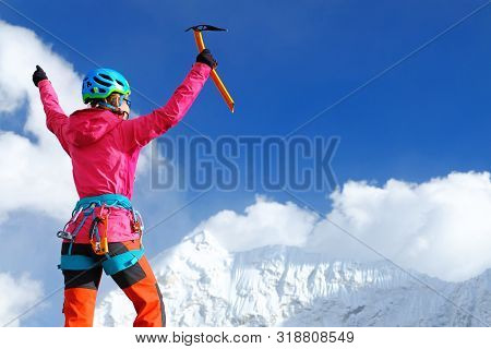 Climber Reaches The Summit Of Mountain Peak Enjoying The Landscape View.
