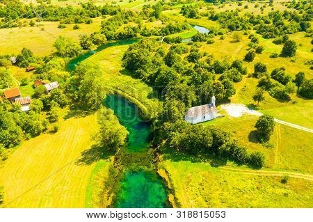 Croatia, Countryside Landscape, Small Stone Church By Gacka River In Region Of Lika, Aerial View