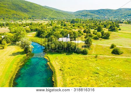Croatia, Countryside Landscape, Small Stone Church By Gacka River In Region Of Lika, Aerial View
