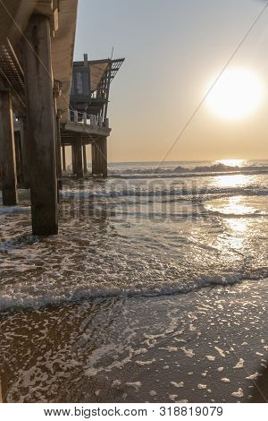 A Close Up View Of The Ocean Water Coming Up Through The Pillers Holding Up The Pier