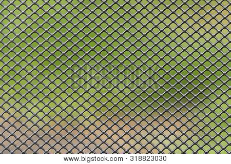 Metal Grid Diagonally Crossed With Blurred Green Brown Background