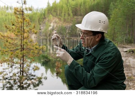 Industrial Ecologist Or Chemist Takes A Sample Of Water From A Flooded Quarry