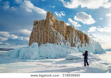 Woman Tourist Takes A Photo On A Smartphone Of A Beautiful Island Covered With Icicles On Lake Baika