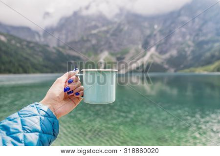 Female Hand Holding Mint Color Enamel Cup. Crystal Clear Lake And Mountains. Tatra National Park, Po