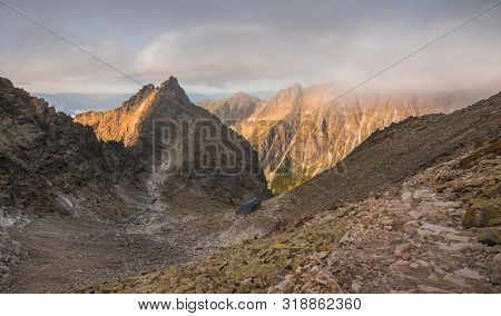 Mountain Landscape With Cottage Under Rysy Peak As Seen From Sedlo Vaha At Sunrise With Golden Light