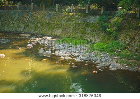 Ciliwung River In Bogor Botanical Garden Flow With Dirt And Trash In Indonesia