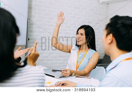 Young Smiling Asian Business Woman Raising Hand Up In The Air And Asking Question In Corporate Meeti