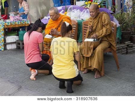 Bangkok, Thailand-september 29th 2014: Two Women Kneel Before Two Monks In Order To Make Merit In Ba