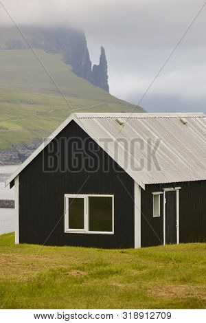 Sea Stack Of Trollkonufingur And Black House. Faroe Islands, Vagar