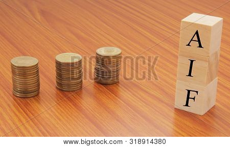 Alternative Investment Funds Or Aif On Wooden Block Letters With Stack Of Currency Coins.