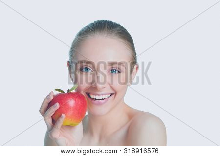 Portrait of happy smiling young beautiful woman eating red apple, over white background