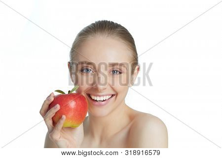 Portrait of happy smiling young beautiful woman eating red apple, over white background