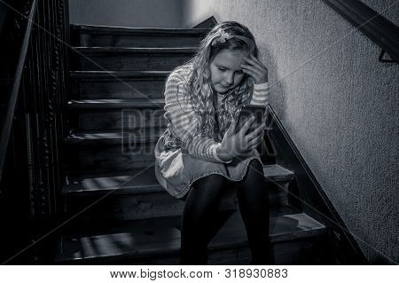 Sad Depressed Unhappy Child Suffering From Cyberbullying By Mobile Smart Phone Sitting Alone.