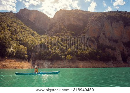 Woman on a kayak in the Pyrenees mountains in Catalonia on the waters of the Mont Rebei Gorge