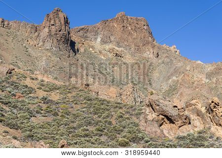 Mountains And Shrubs Near The Volcano Teide, Partially Covered With Clouds. Bright Blue Sky. Teide N
