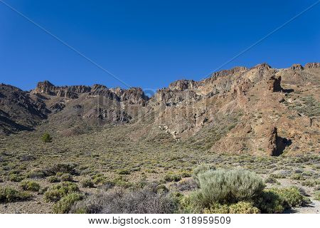 Mountains And Shrubs Near The Volcano Teide, Partially Covered With Clouds. Bright Blue Sky. Teide N