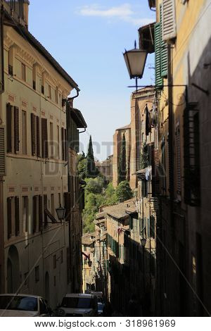 Ancient Tuscan Walled City Houses With Towers And Stone Walls And Paved Cobbled Streets In Italy