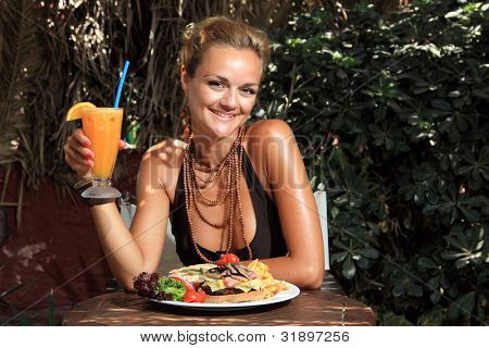 Donna mangiare un cheeseburger gustoso e fresco jiuce arancione