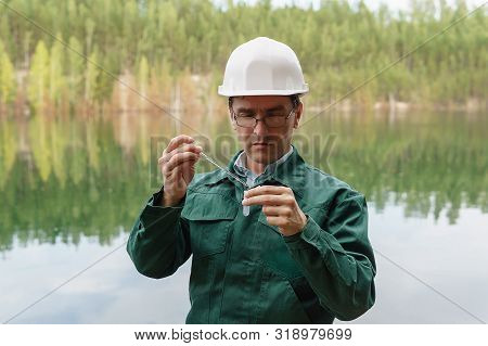 Industrial Ecologist Or Chemist Takes A Sample Of Water From Lake At The Site Of A Flooded Quarry