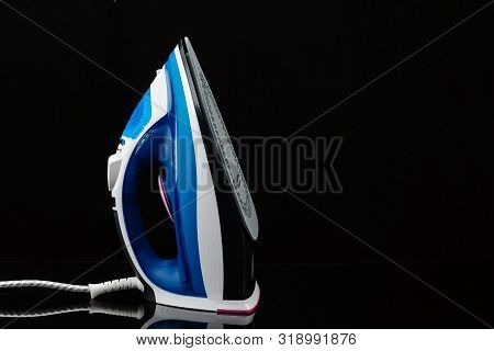 Electrical Blue And White Hand Iron On The Black Mirror Background With Copy Space