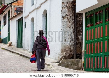 Mongui, Colombia - August, 2019: Woman Dressed With Traditional Hat And Ruana At The Beautiful Stree