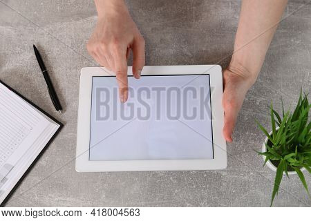 Woman Using Tablet With Blank Screen At Grey Stone Table, Top View. Space For Text