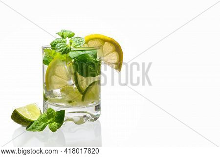 Citrus Lemonade With Ice In A Glass Decorated With Lemon, Lime And Mint Slices And On A White Backgr