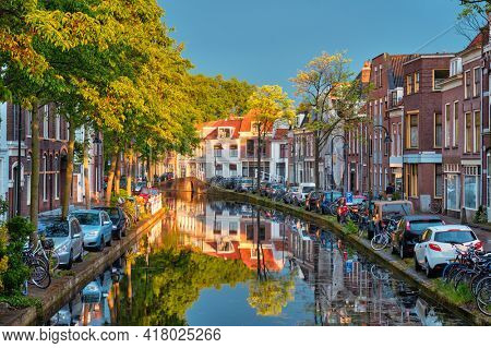 Delt canal with old houses and cars parked along on sunset