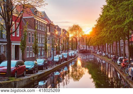 Delt canal with old houses and cars parked along on sunset