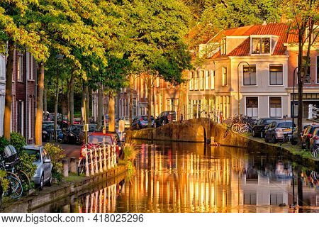Delt canal with old houses and cars parked along on sunset