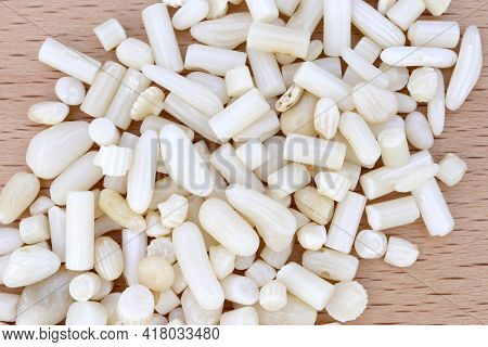 White Coral Heap Up Jewel Stones On Light Varnished Wood Texture. Pile Mineral Pebbles Background.