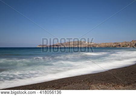 Coast And Beach Of Vlychada On Santorini Island In Greece. In The Background Blue Sky And Waves At S