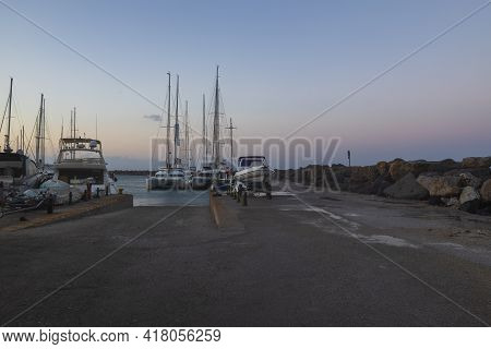 Boats In Vlichada Harbor On Santorini Island In Greece In The Morning At Sunrise. The Background Is 