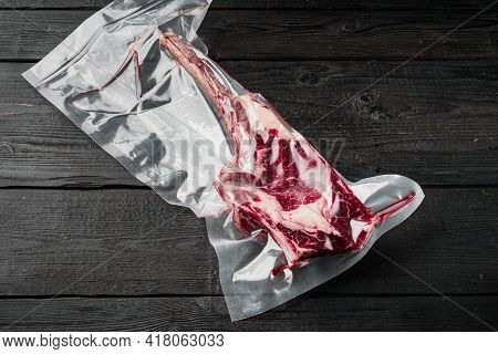 Tender Raw Trimmed Bone-in Ribeye Tomahawk Steak In Pack Set, On Black Wooden Table Background, With