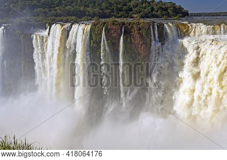 Water Rushing Over The Red Cliffs At Iguazu Falls In Iguazu Falls National Park In Argentina