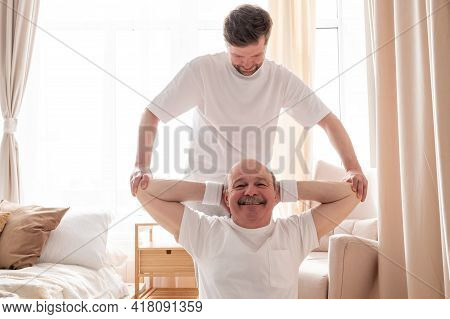 Male Yoga Trainer Helps To Senior Man To Do Asana Correctly.
