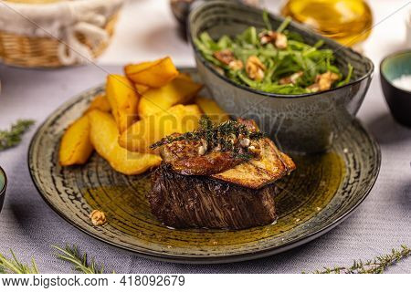 Steak With Grilled Duck Liver Served With Potato Wedges And Aragula