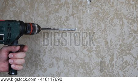 Husband Or Handyman Drills Hole In Marbled Painted Plaster Wall Surface. Male Hands Hold Electric Dr