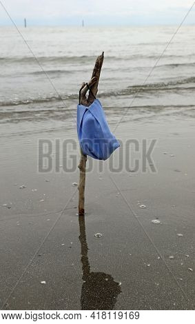 Surgical Mask On The Seashore Hanging On The Stick Like A Flag At Half Mast