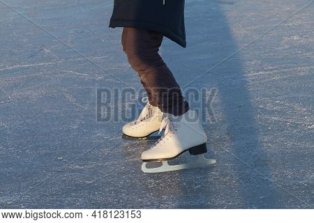 A Child In White Skates Clumsily Rides In Winter On The Ice Of A River Or Lake