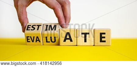 Estimate Or Evaluate Symbol. Businessman Turns Wooden Cubes And Changes The Word 'evaluate' To 'esti