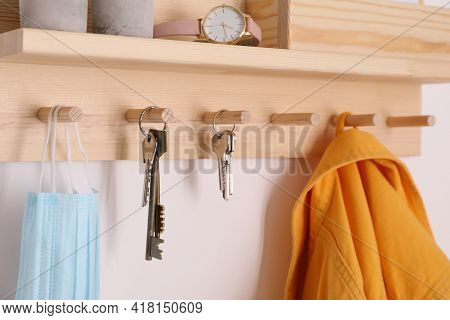 Wooden Hanger For Keys With Different Stuff On White Wall, Closeup
