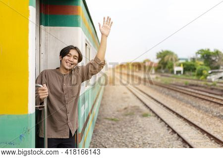 Handsome Young Asian Man Hand To Say Hello Or Goodbye To Friend On Train, Waving Goodbye