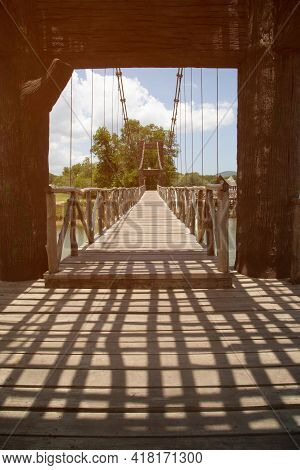 Dark Shadow In The Daytime On A Wooden Suspension Bridge That Crosses A Reservoir In A Park In Thail