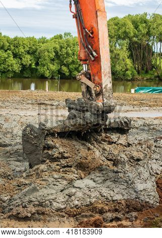 Digger Bucket Scooping Up A Lot Of Mud That Cme Out Of A River.