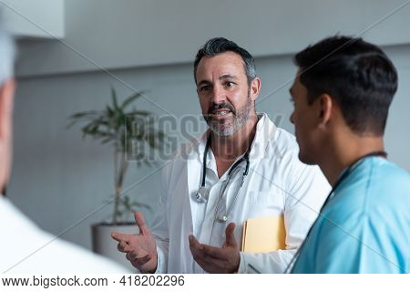 Diverse male doctors standing in hospital corridor and having discussion. medicine, health and healthcare services.