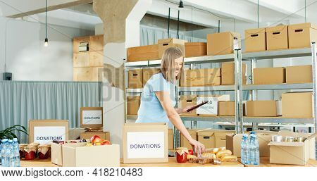 Portrait Of Busy Caucasian Mature Pretty Woman Volunteer Working In Charity Center Warehouse Packing