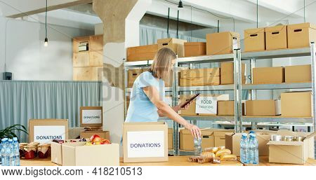 Portrait Of Busy Caucasian Mature Pretty Woman Volunteer Working In Charity Center Warehouse Packing