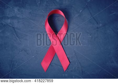 Red Ribbon On Concrete Texture Background, Symbol Of Aids Disease And Drug Abuse Problem.