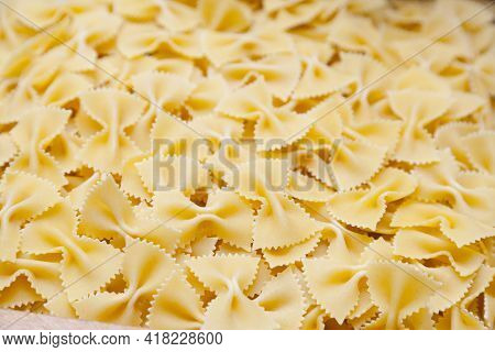 Raw Food Composition - Yellow Farfelle Pasta In A Basket.